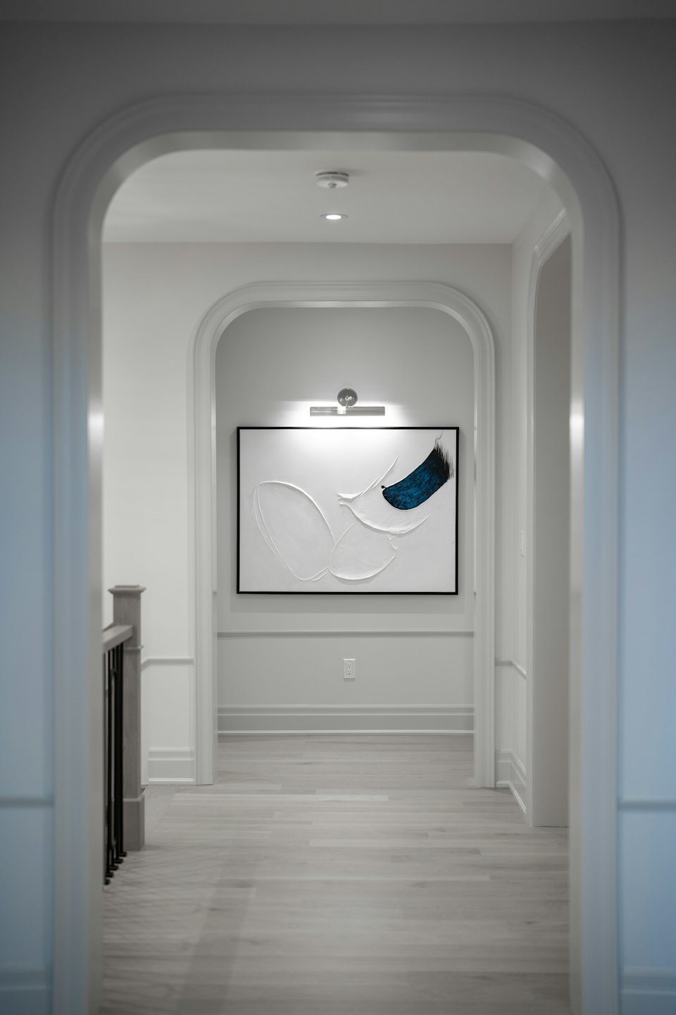 Moderner Flur in einem Wohnhaus mit weißen Torbögen und abstrakter Wandkunst.